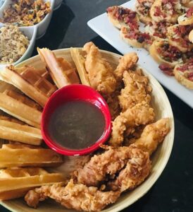 A platter with fried chicken tenders, spring rolls, and dipping sauce.