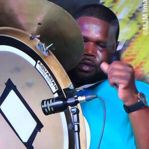 A focused drummer playing the bass drum during a performance.